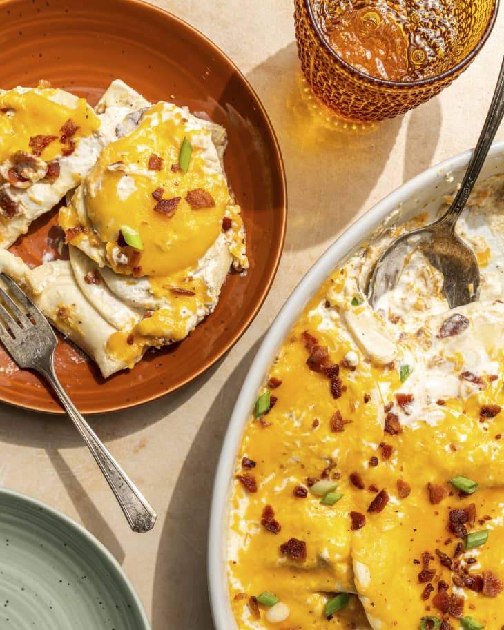 Pierogi Casserole with a portion scooped out onto a rust colored plate next to it, with a fork on the plate. There is also a rust colored glass and turquoise plate.
