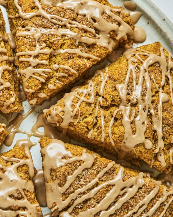 a closeup of pumpkin scones, originally baked into the round shape of a pie and then cut into six slices, with icing drizzled on top.