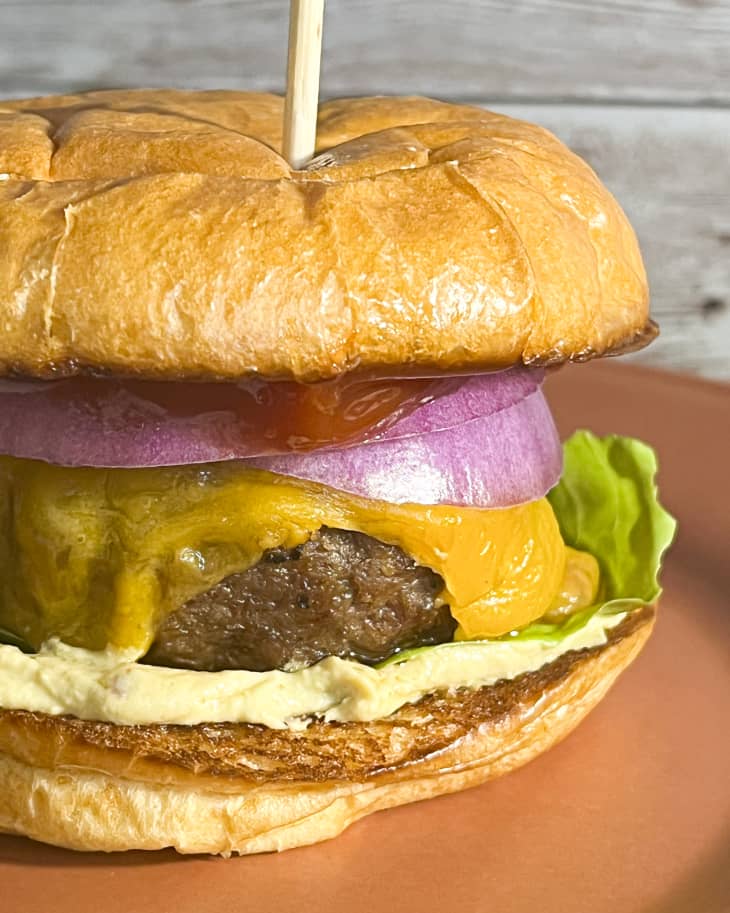 a cheeseburger with a red onion and lettuce on an orange plate