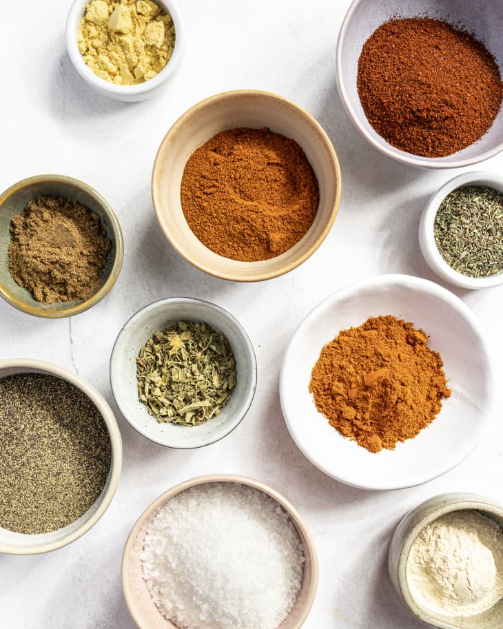 a variety of colorful spices in small, round, ceramic dishes, photographed from above