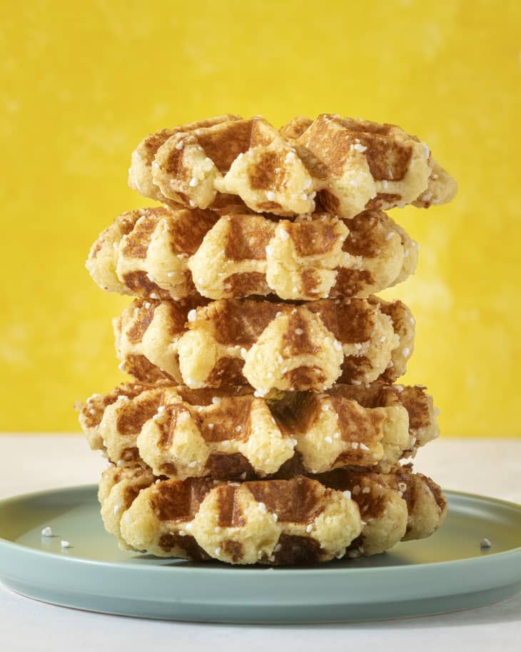 a stack of liege waffles (A Liège waffle is filled with unevenly distributed clusters of caramelized pearl sugar) on a blue plate with a yellow background