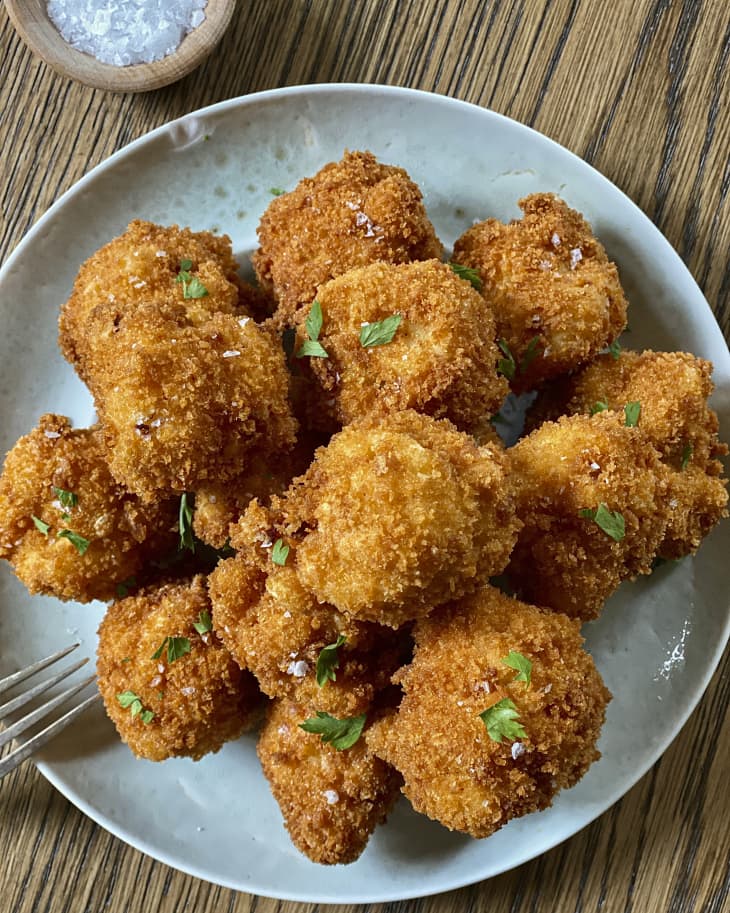 fried mac and cheese balls stacked on a blue plate with a fork on the side