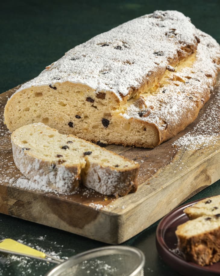 a loaf of of Stollen (a rich German fruit and nut christmas bread) with a slice cut off and powdered sugar on the side