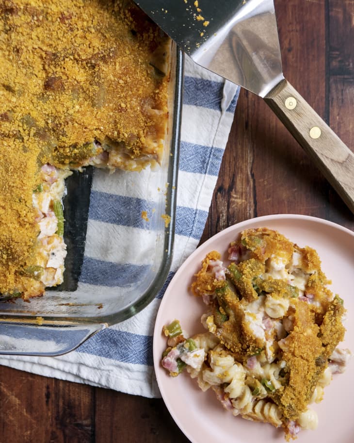 a piece of Chicken Cordon Bleu Casserole on a pink plate with the rest of the casserole in a dish nearby