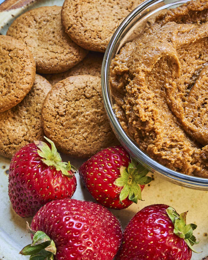 cookie butter in a bowl, with cookies and strawberries on the side
