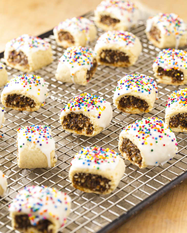 Cucidati (Italian fig cookies, where the outer cookie is pastry dough, covered with icing and topped with rainbow sprinkles) on a cooling rack