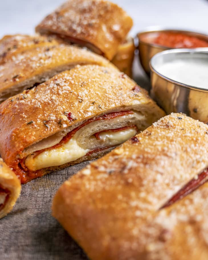 pepperoni bread (pepperoni and cheese baked into a roll), sliced open so that you can see the inside with a white dipping sauce on the side
