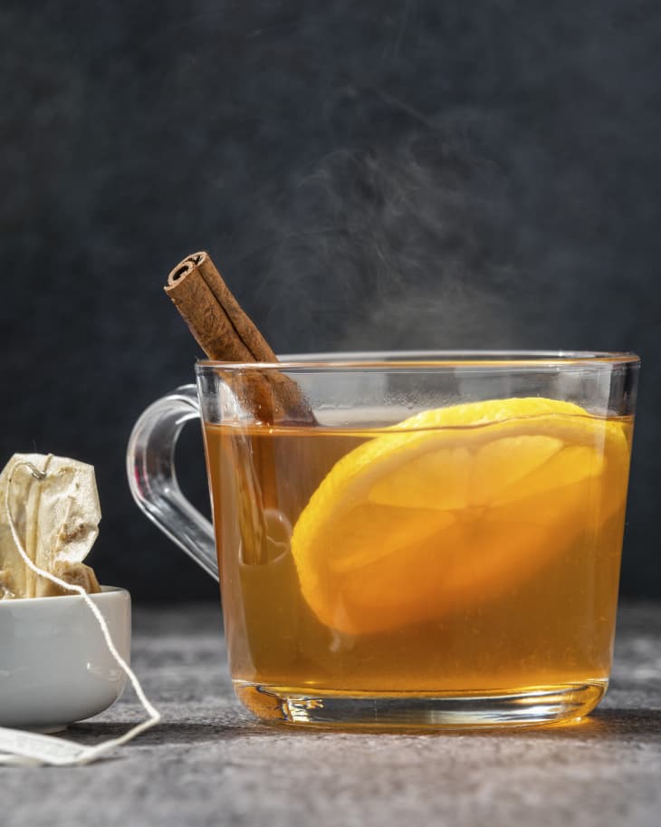 A Tea Hot Toddy in a clear glass mug with a cinnamon stick and a lemon slice.