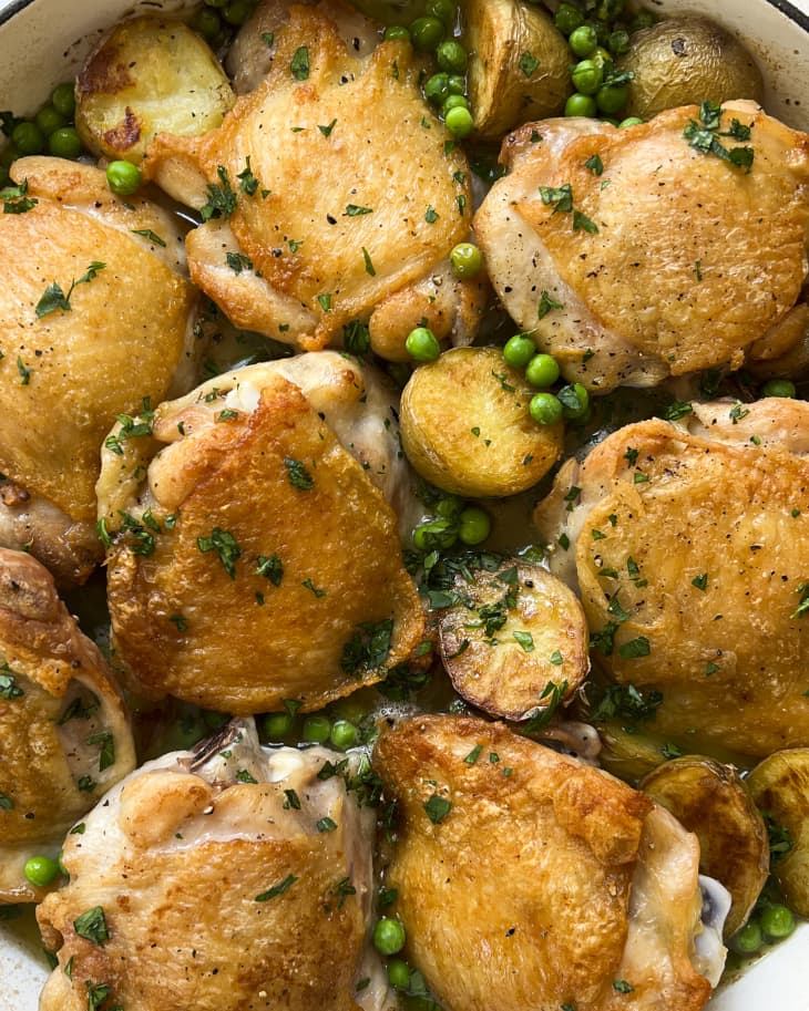 Chicken Vesuvio with peas in a white cooking pot.