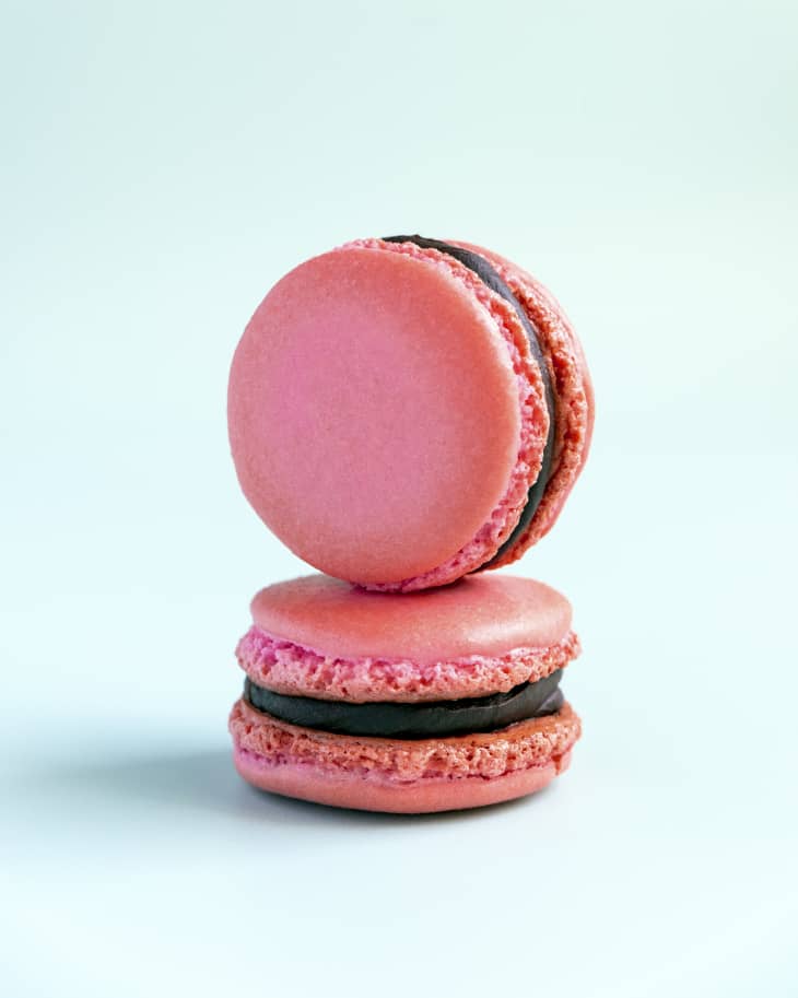 two pink Macarons with chocolate filling, with one balanced on top of the other.