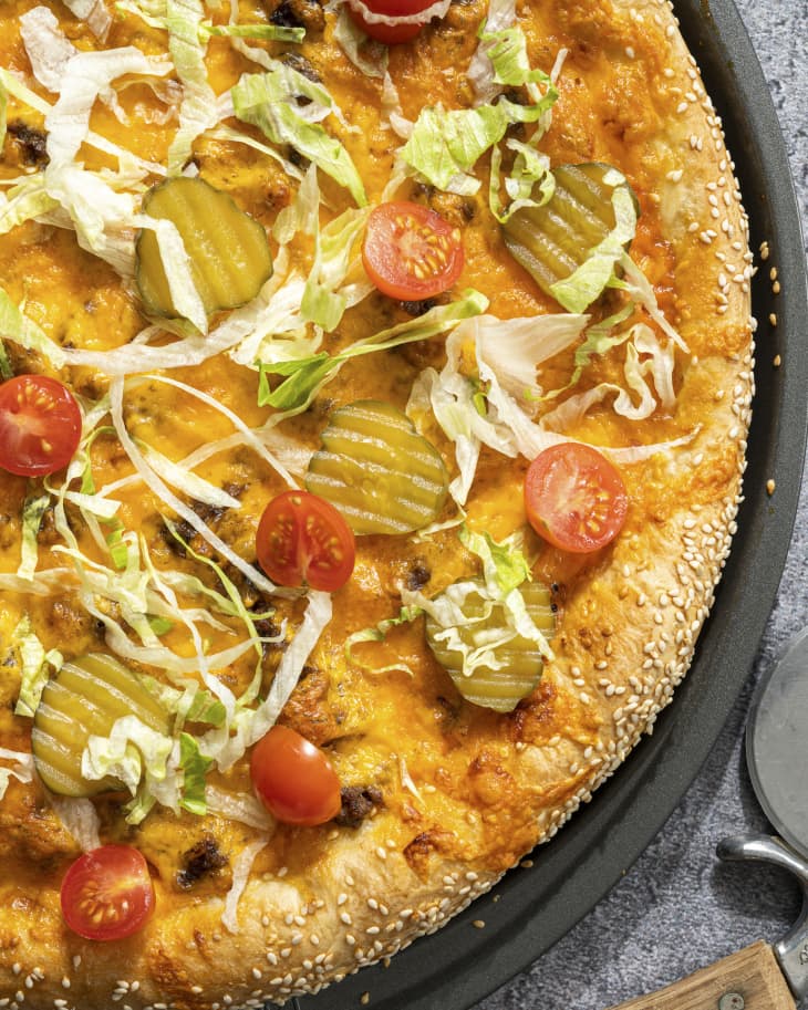 A whole pizza with a deconstructed cheeseburger toppings