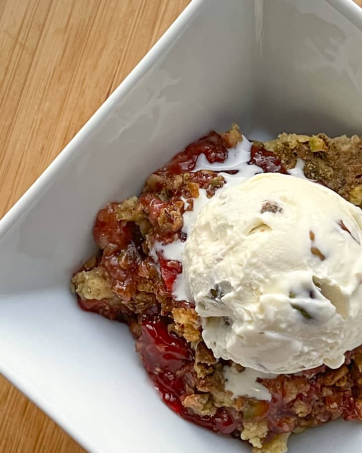 Cherry dump cake in a square bowl topped with ice cream