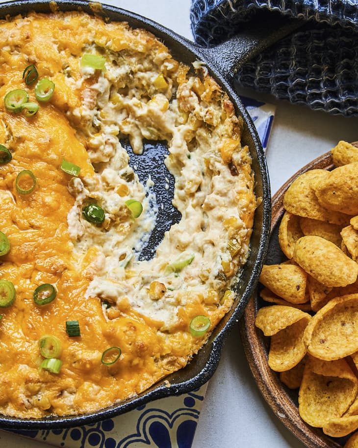 Corn dip is a spin on classic baked dips that uses a cream cheese, mayonnaise, and sour cream base to create a creamy and cheesy concoction. The other flavors accent and build upon the base, here green chile, garlic, scallion, lime, and cheddar cheese