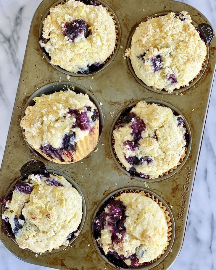 six lemon blueberry muffins in a baking pan.