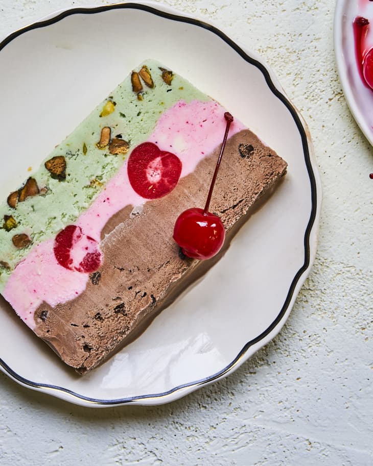 a slice of Spumoni ice cream cake (a layered combination of pistachio, cherry and chocolate ice cream with whole cherries inside)