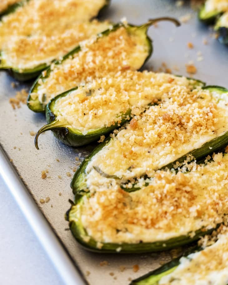 stuffed jalapenos (Jalapeno pepper sliced in half, stuffed with cheese and breadcrumbs) on a silver baking sheet
