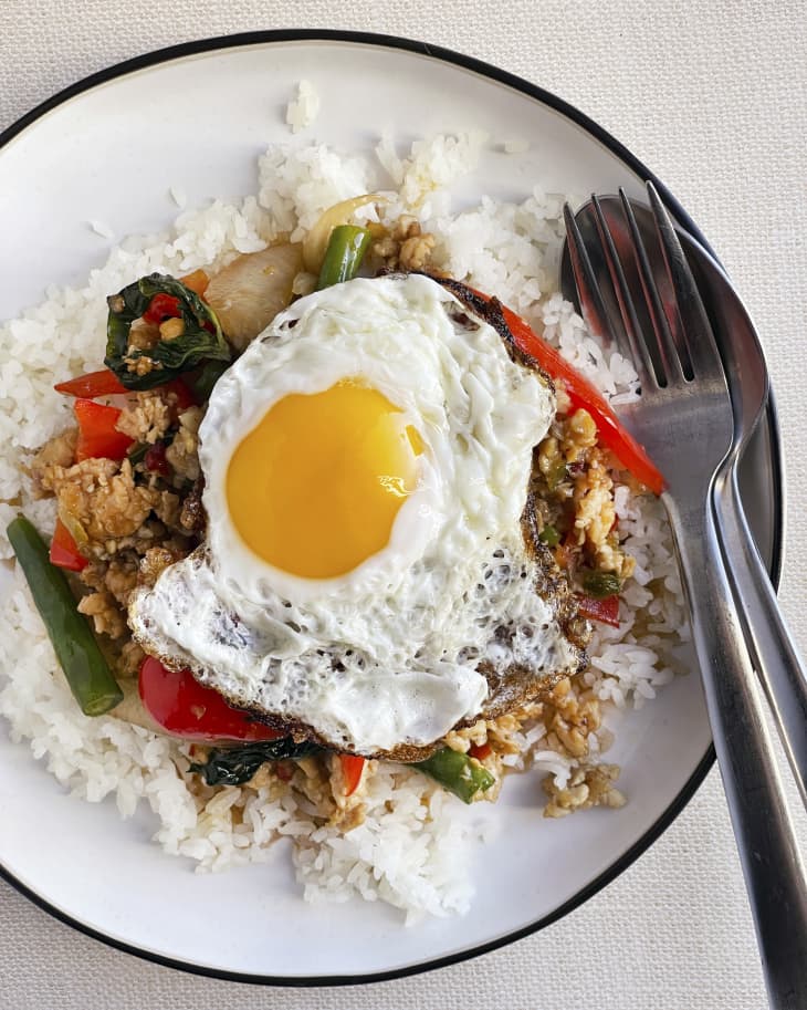 thai basil chicken on a bed of rice with a fried egg on top.