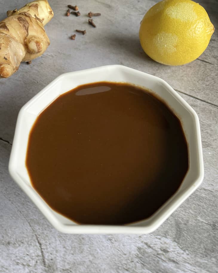 Worcestershire sauce in a white angled bowl with a lemon and ginger root in the background