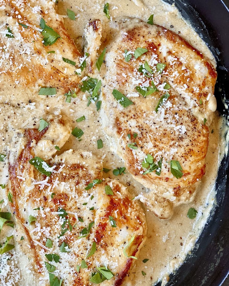 chicken breasts in a creamy brown sauce with a green garnish on top