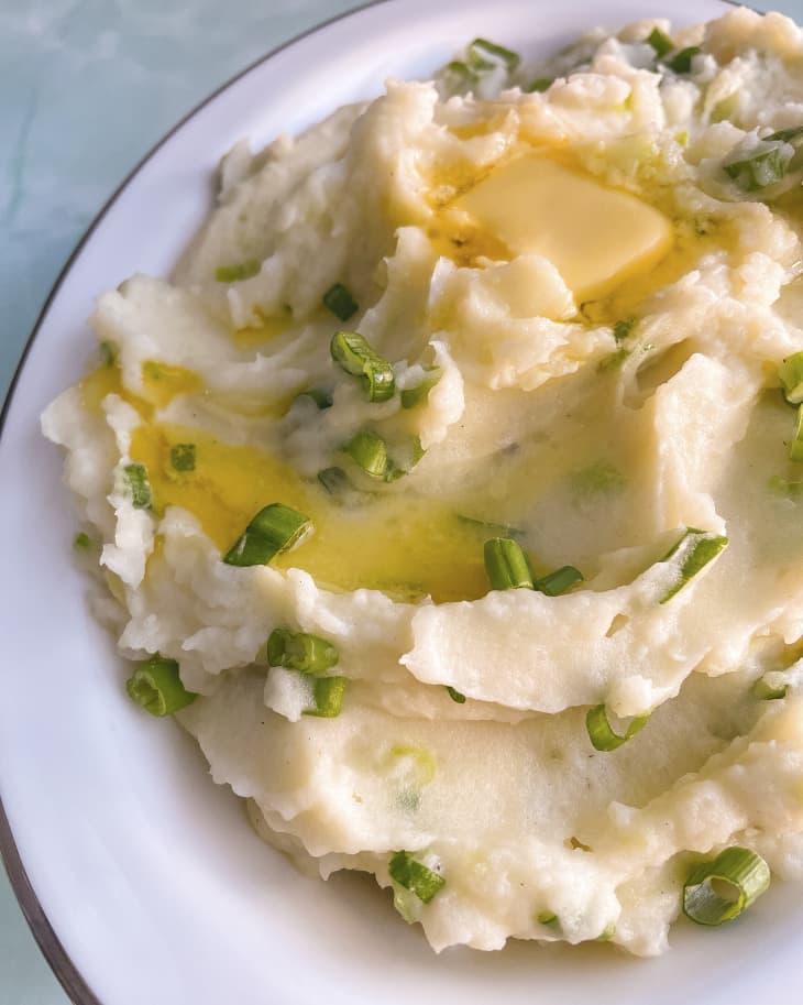 Irish Champ, which is made of green onions and mashed potatoes, on a white plate.