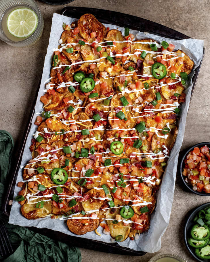 Irish nachos (thinly sliced potatoes, crispy bacon, melted cheese, drizzled sour cream) in a sheet pan