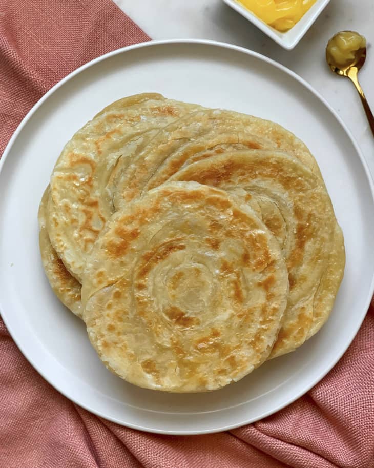 A stack of round Paratha (a flatbread native to the Indian subcontinent) on a round white plate