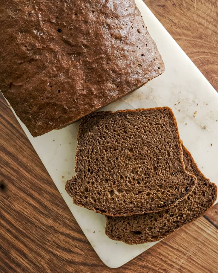 a load of pumpernickel bread with two slices cut off and laid down on a cutting board.