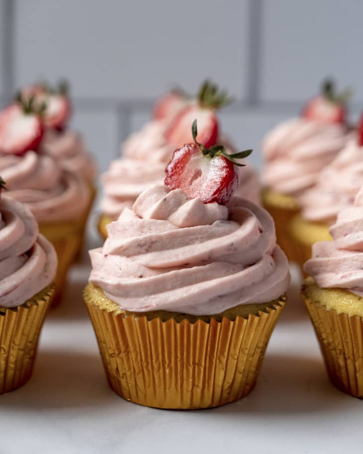 cupcakes with pink swirled frosting and a single strawberry on top.
