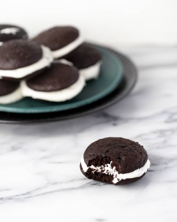 whoopie pies on a plate, with one with a bite taken out off the plate.