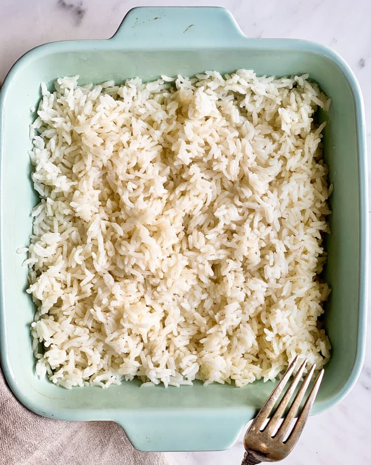 a square, pale blue baking dish with white rice in it and a fork on the side