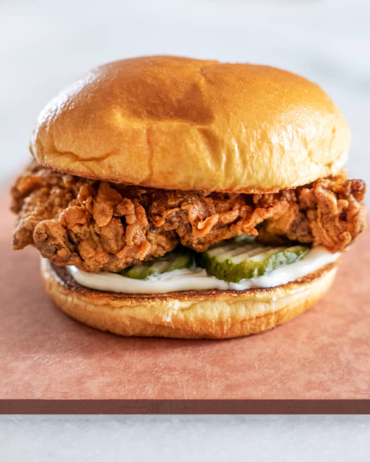 a fried chicken sandwich on a bun with pickles and mayo
