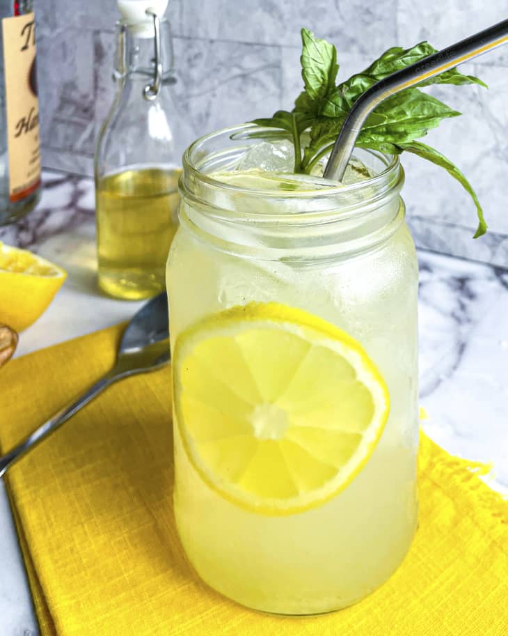 a mason jar with vodka lemonade, with a round slice of lemon floating in the middle, a sprig of mint and a metal straw
