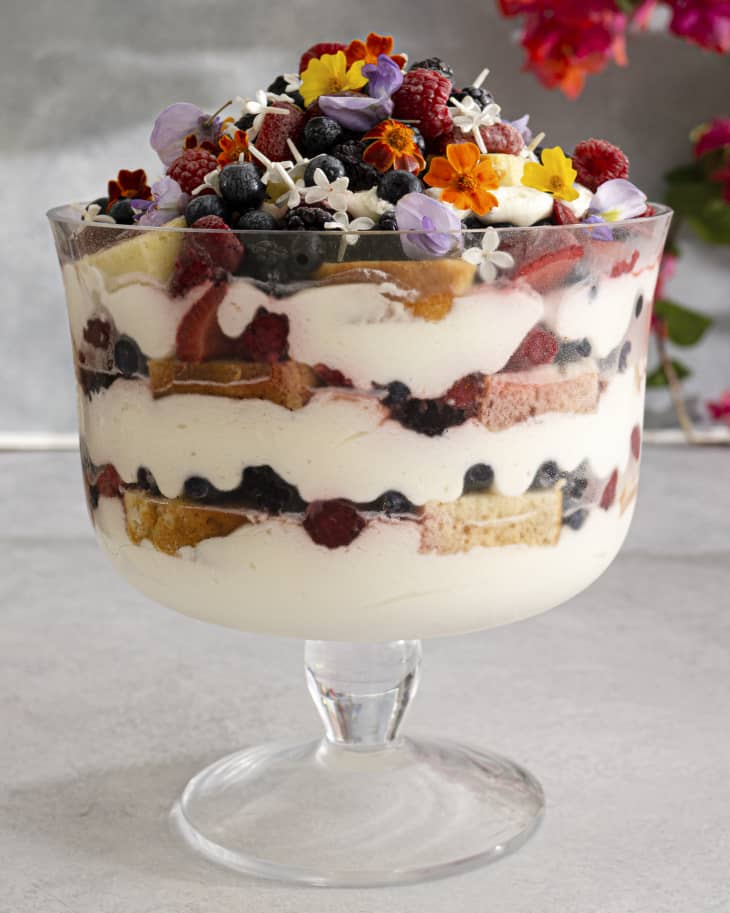 A berry trifle with various berries and colorful edible flowers on top.