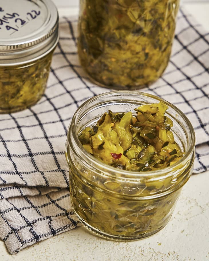 a photograph of pickle relish in a small jar with two other jars of pickle relish in the background.
