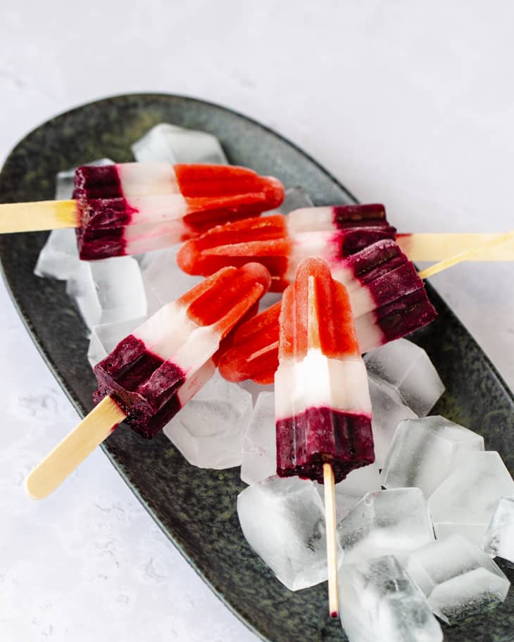 Red white and blue popsicles on a bed of ice, on an oval black plate.