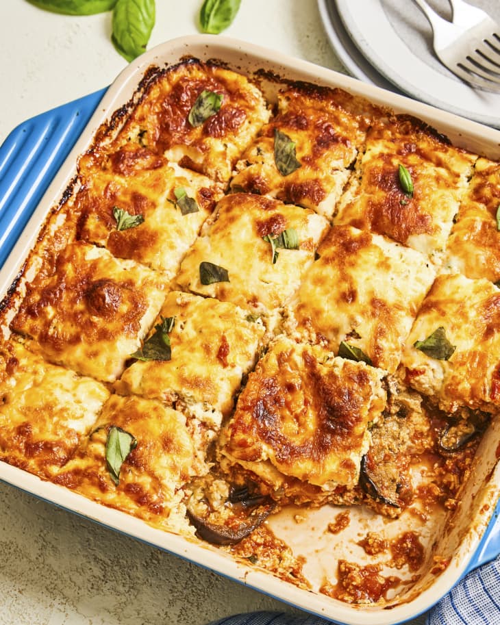 A photo of a square dish of baked eggplant casserole, that looks similar to lasagna, cut into squares with a few pieces missing.