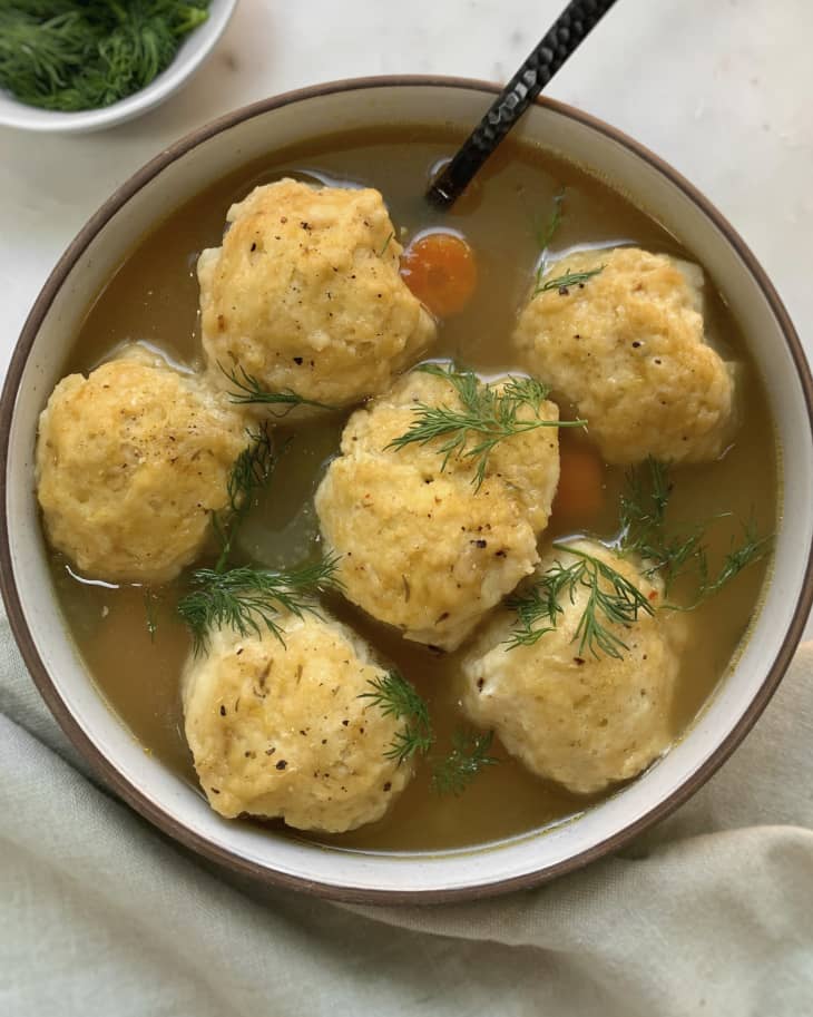 A photo of dumplings in a bowl with a spoon resting on the side.