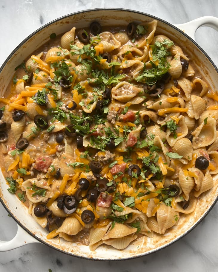 A photo of a round bowl with pasta shells and taco ingredients tossed together.