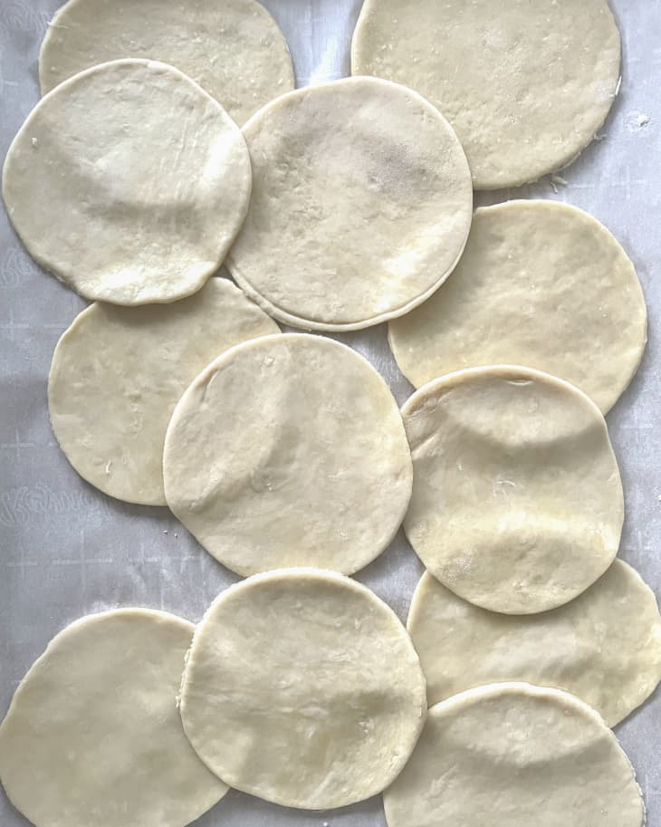 A photo of a round pieces of empanada dough overlapping each other.