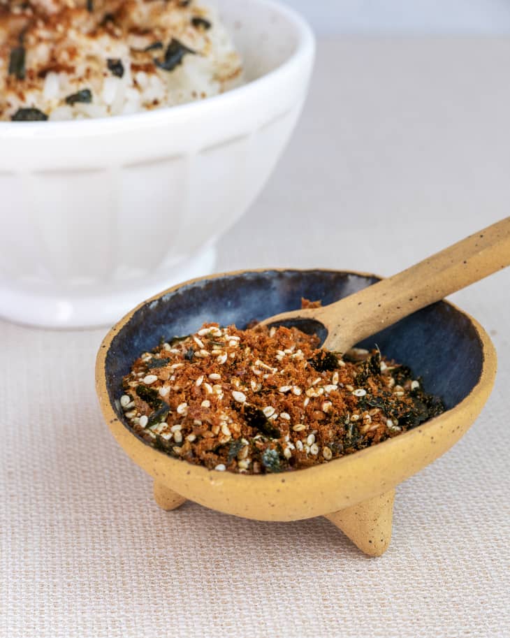 A photo of a small clay bowl with furikake, which is a basic blend made from a base of crushed or sliced nori seaweed blended with sesame seeds, sugar and salt