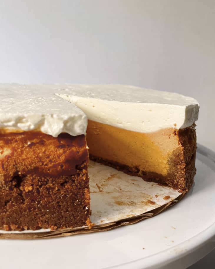 A photo of a whole sweet potato cheesecake on a plate with a slice missing.
