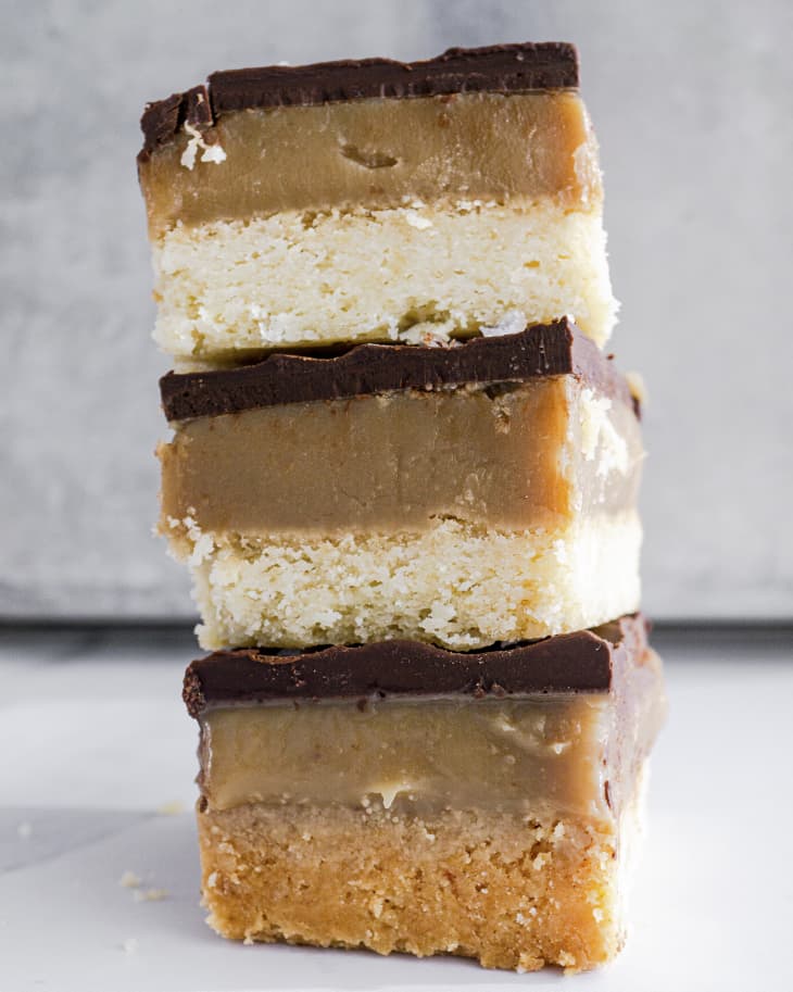 A photo three Millionaires shortbread bars (also known as caramel bars- a biscuit confectionery item composed of a square, shortbread biscuit base topped with caramel and milk chocolate) in a stack.