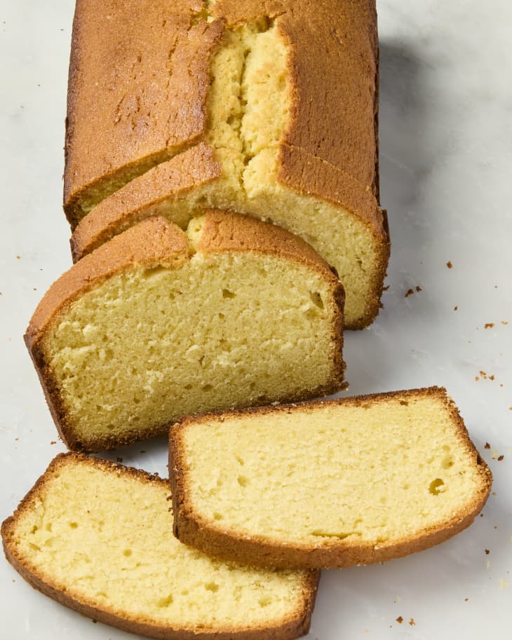 overhead shot of a pound cake loaf cut into three slices, on a marble surface.