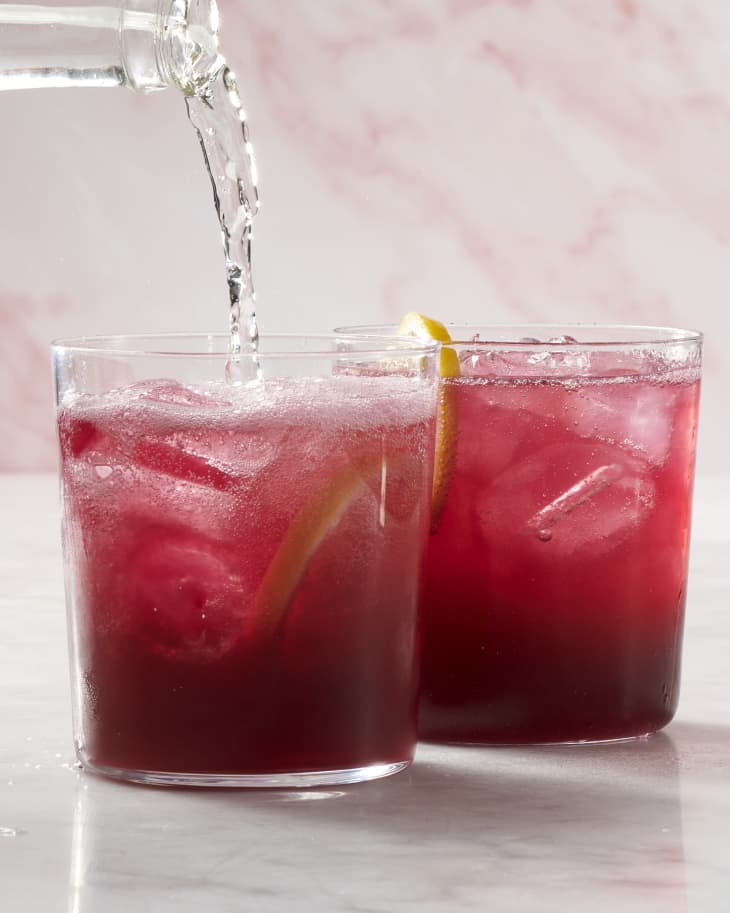 A photo of 2 glasses of red tinto de verano cocktails. The glass in the front is getting seltzer poured in.