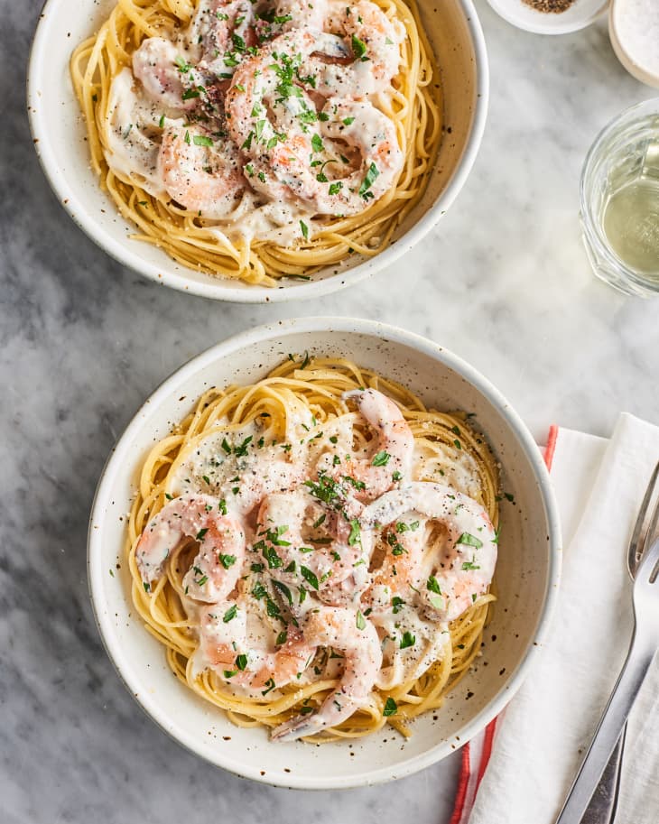 2 bowls of pasta topped with a creamy, garlic shrimp sauce