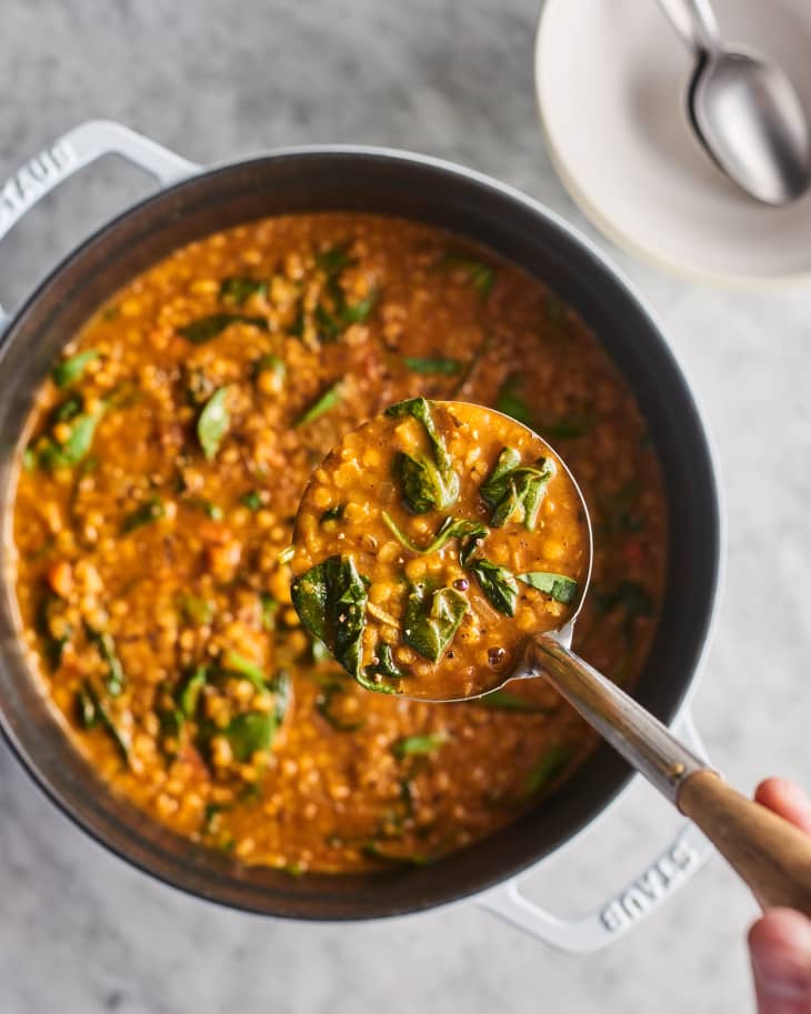 Ladling some lentil soup out of a dutch oven