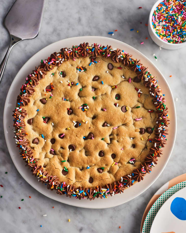 overhead view of chocolate chip cookie cake with chocolate frosting and rainbow sprinkles