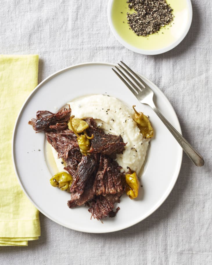 A plate of pot roast with peppers and mashed potatoes.