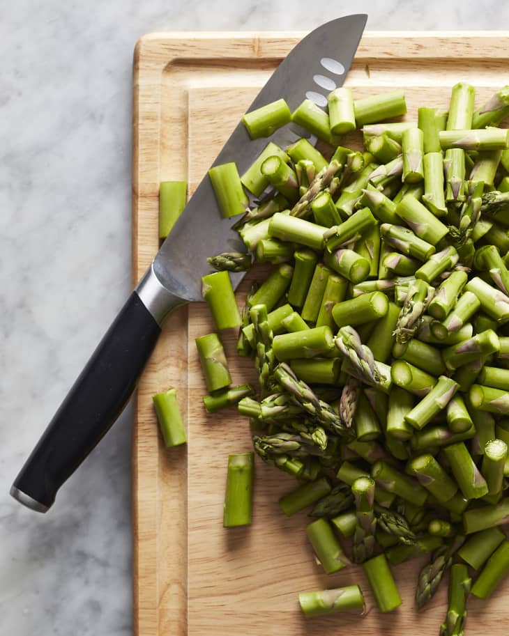 Cutting board with chopped asparagus. Knife is in photo