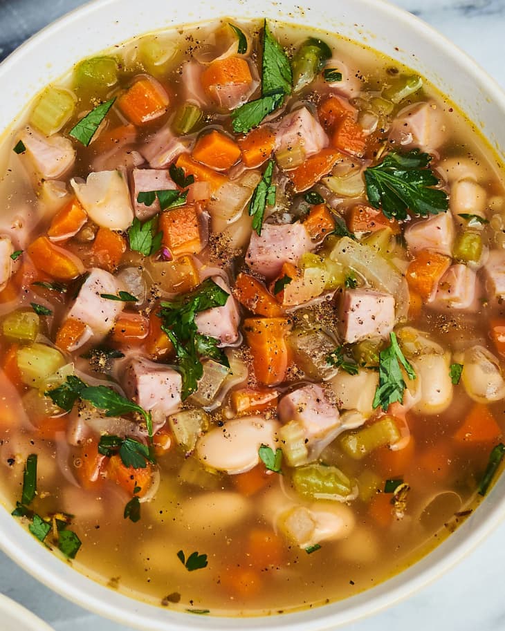 A bowl of ham and bean soup sits on the kitchen counter.